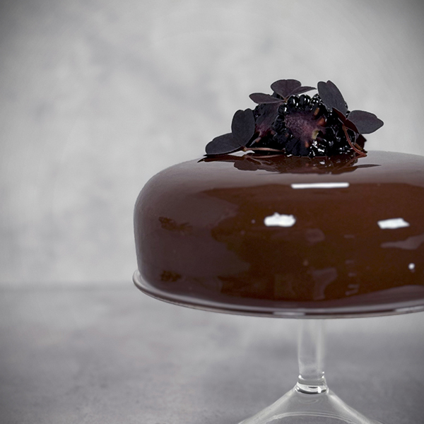 Mjölkchokladmoussetårta med en intrigör på bjönbärspannacotta med vaniljyoghurt och björnbärsgelé. På en botten av brownie med brynt smör och pekannötter. Dekorerad med en choklad mirror glaze, björnbär och röd oxalis